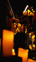 Candlelight illuminates the stage where a double bass musician plays. A stage drowning in a sea of...