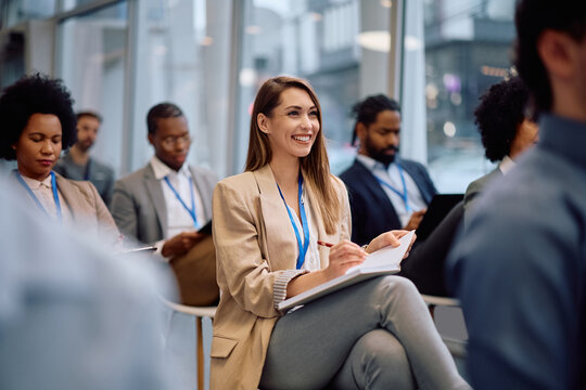 Young happy businesswoman attending a seminar in conference hall.