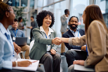 Happy businesswoman greeting her colleagues on seminar in board room.