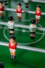 Fototapeta premium Foosball table with players representing Sport Lisboa e Benfica and Sporting Clube de Portugal, highlighting a friendly football rivalry in a playful setting.