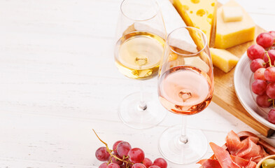 A delectable arrangement of various cheeses, fresh grapes, prosciutto and wine