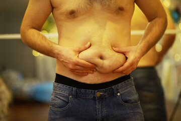 Close-Up of Man Grabbing Belly Fat, Demonstrating Weight Gain and Body Image Concerns
