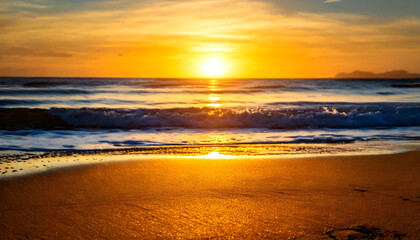 Obraz premium Stunning sunset over a tranquil ocean, golden light illuminating the sandy beach. Perfect for travel, vacation, or nature themes. Evokes serenity and warmth.