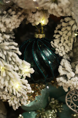 Festive Green Christmas Ornament Hanging on Snow-Covered Tree Branches
