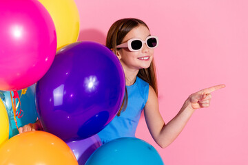 Obraz premium Young girl in bright colors having fun against a pink background with balloons