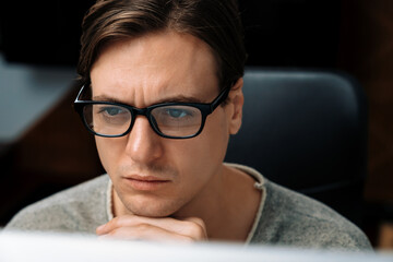 Portrait stressful businessman wearing glasses in dark light, manager looking on pc on creative...
