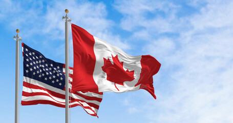 Canada and american national flags waving in the wind on a clear day