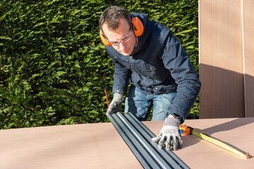 Male using ruler to measure board before cutting using a electric saw