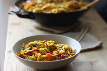 Bowl of stir fry vegetables and noodles, served on the table. Selective focus.