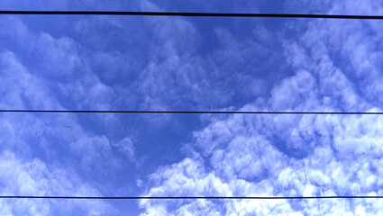 Fototapeta premium The morning started with stratocumulus clouds filling the sky, bright and filled with a beautiful blue color among the power lines.