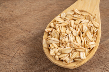 Rolled oats in a wooden spoon on a rustic wooden surface, showcasing natural and healthy ingredients for nutritious meals and recipes.