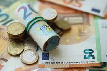Roll of euro currency money bills and many euro cents on banknotes of european union