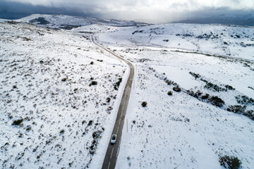 an electric car driving on a mountain road after a snowstorm. winter transportation concept...