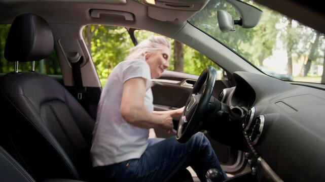 Happy satisfied glad Caucasian elderly female mature senior woman car auto driver open door sit inside automobile vehicle fastens seat belt buckle up adjusting rearview mirror preparing drive machine