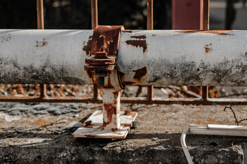 Rusty pipe with damaged support on a concrete surface in an abandoned area under natural light