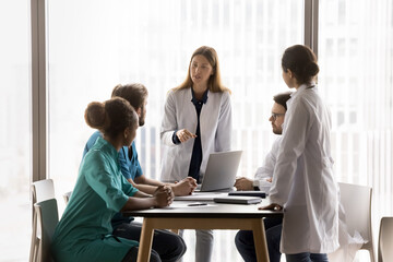 Diverse young healthcare specialists take part medical concilium led by Caucasian female hospital...