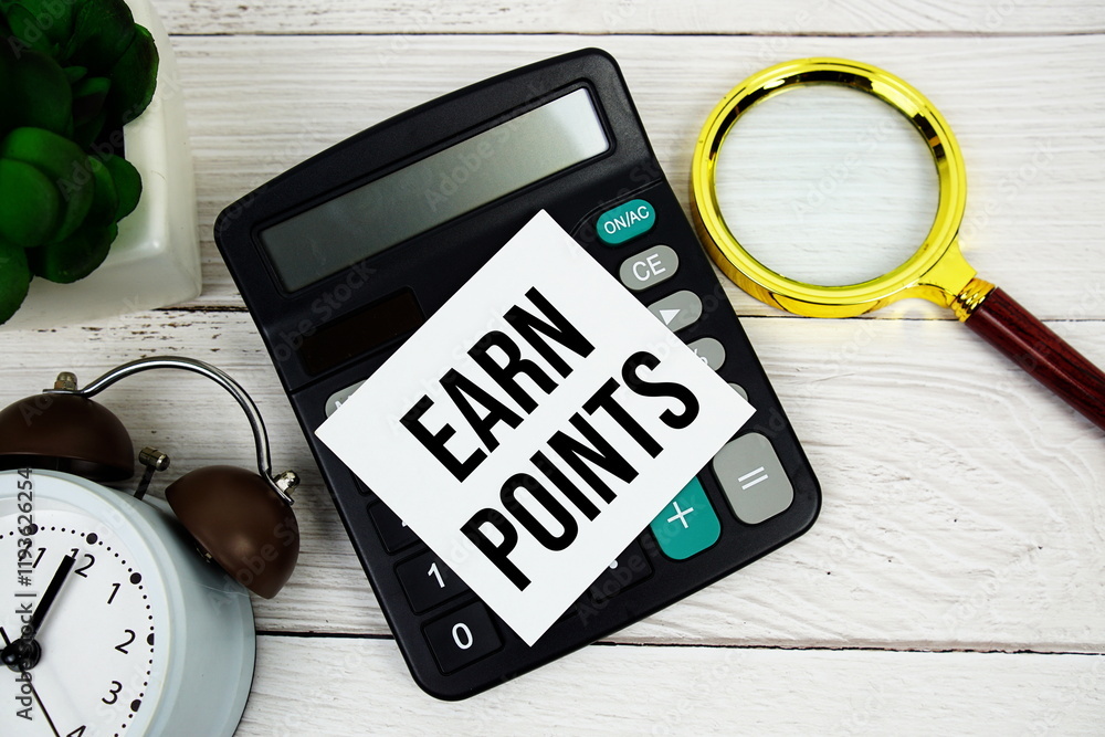 Poster earn points text message on sticky note with magnifying glass, alarm clock and calculator on wooden 