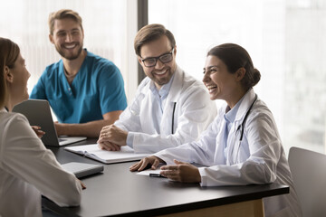 Multiethnic young doctors, medical staff engaged in discussion, sharing insights or advices, during...