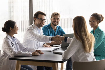 Group of healthcare professionals gathered around table, accomplish team meeting or discussion with...