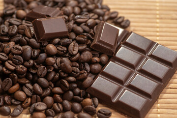 Broken dark chocolate and coffee beans on a wooden table