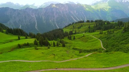 Cyclist on gravel road amidst stunning alpine scenery of Fellhorn and Kanzelwand in Germanys Bavarian Alps. Aerial view of summer adventure with green mountains, trails, and breathtaking panoramas. 