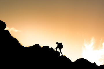 Man climbing up a mountain ready for challenge before him. Believe in yourself, overcoming challenges, pushing forward concept.	