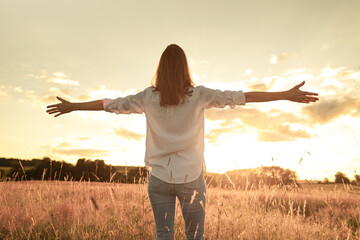 Happy joyful young woman with open arms enjoying sunshine peace serenity in nature 