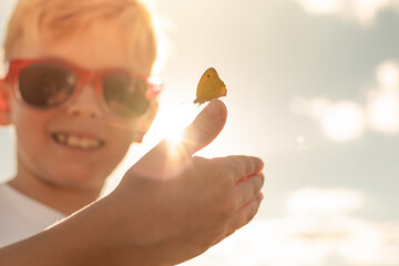 Happy child with butterfly landing on hand, nature love protect beauty 