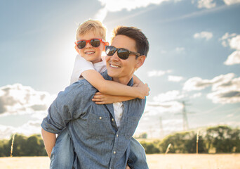 father and son in the park. father's day happy family child dream concept. father carries his son on his back. dad playing with his son in nature in the park at sunset lifestyle
