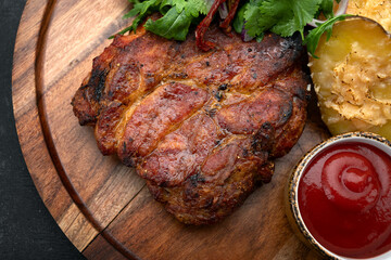 Grilled meat steak with spicy sauce, baked potato and herbs with onions