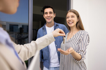 Happy couple buying new house, getting key from realtor, meeting with seller, real estate agent...