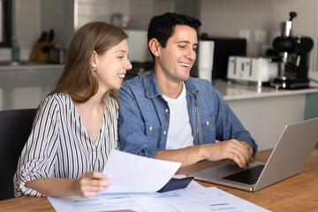 Happy financially successful young couple counting profit, checking income analytics, using bank...