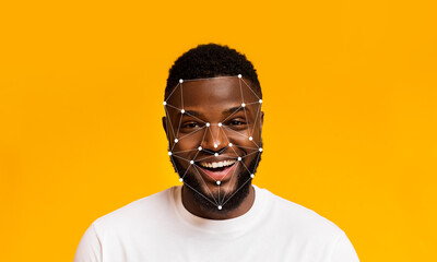 A person smiles brightly against a yellow backdrop while facial recognition technology detects...
