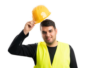 Builder man with friendly expression taking off helmet gesture