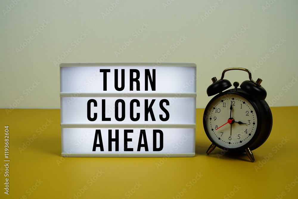 Poster turn clocks ahead text on light box with alarm clock on yellow background