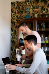 two lgtbi couple boys drink coffee at home while looking at the computer