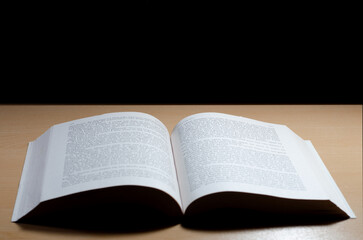 Fototapeta premium Open Book on Wooden Table with Black Background