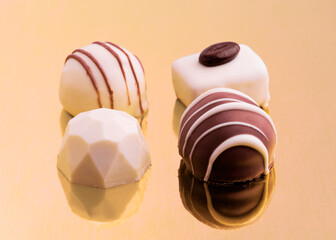 Delicious assorted chocolates on a golden reflective surface during a special occasion