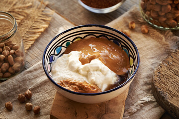Greek yogurt in a bowl with nut butter, maple syrup and hazelnuts - ingredients for making healthy sweets