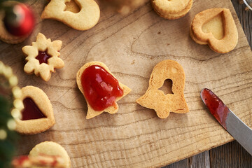 Filling homemade Linzer Christmas cookies with red marmalade