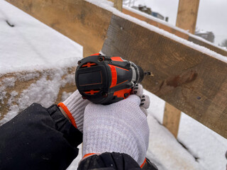 Master hands are drilling a wooden beam with a cordless drill. Detailed view of the tool
