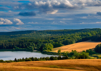 Obraz premium a landscape photograph of a beautiful countryside. The sky is blue with a few white clouds scattered across it