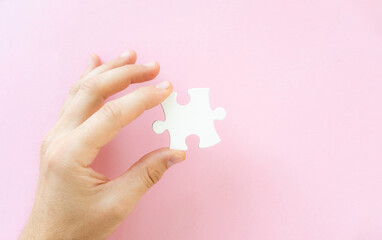 Hand holding white piece of jigsaw puzzle, top view