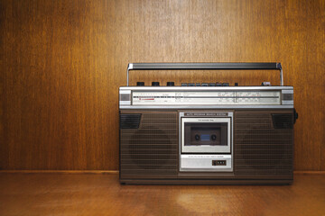 Vintage 1980s Boombox with Cassette Player and Analog Radio Tuner on Wooden Surface, Retro Portable Audio System with Built-in Speakers and Nostalgic Classic Design for Music and Style Enthusiasts
