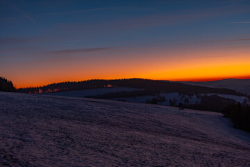 Orange sky shining through the forest at sunset