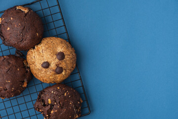 American oatmeal cookies with chocolate drops and raisins on the blue background. Sugar consumption concept. Flat lay of pastry with copy space