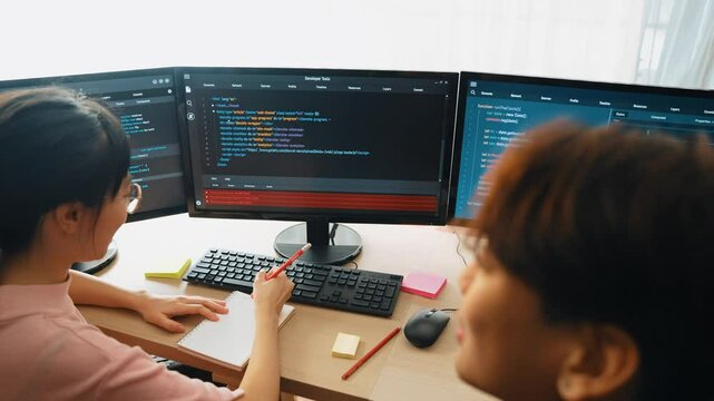 Slow motion back end software developer engineer for computer programming working together on debugging writing computing code, solving complex algorithms display on monitor in office. Burgeoning