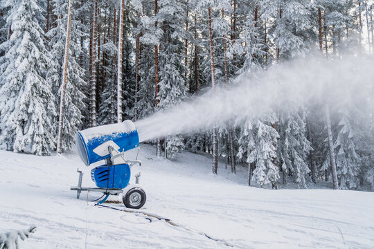 Blue snowmaking snow cannon spraying artificial snow for ski slopes in European alpine ski resort
