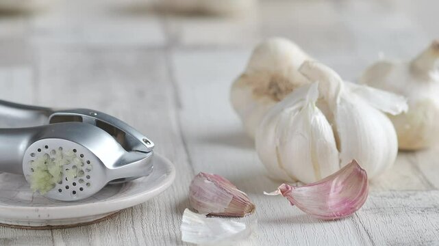 Fresh organic garlic bulbs, cloves and pressed garlic on wooden background. Selective focus