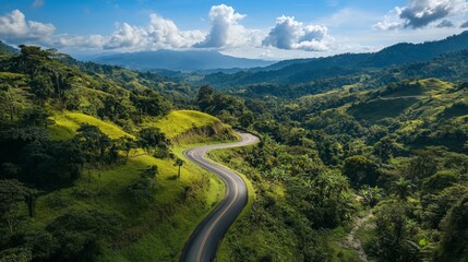 Serene winding road through lush green hills under vibrant blue sky and fluffy clouds